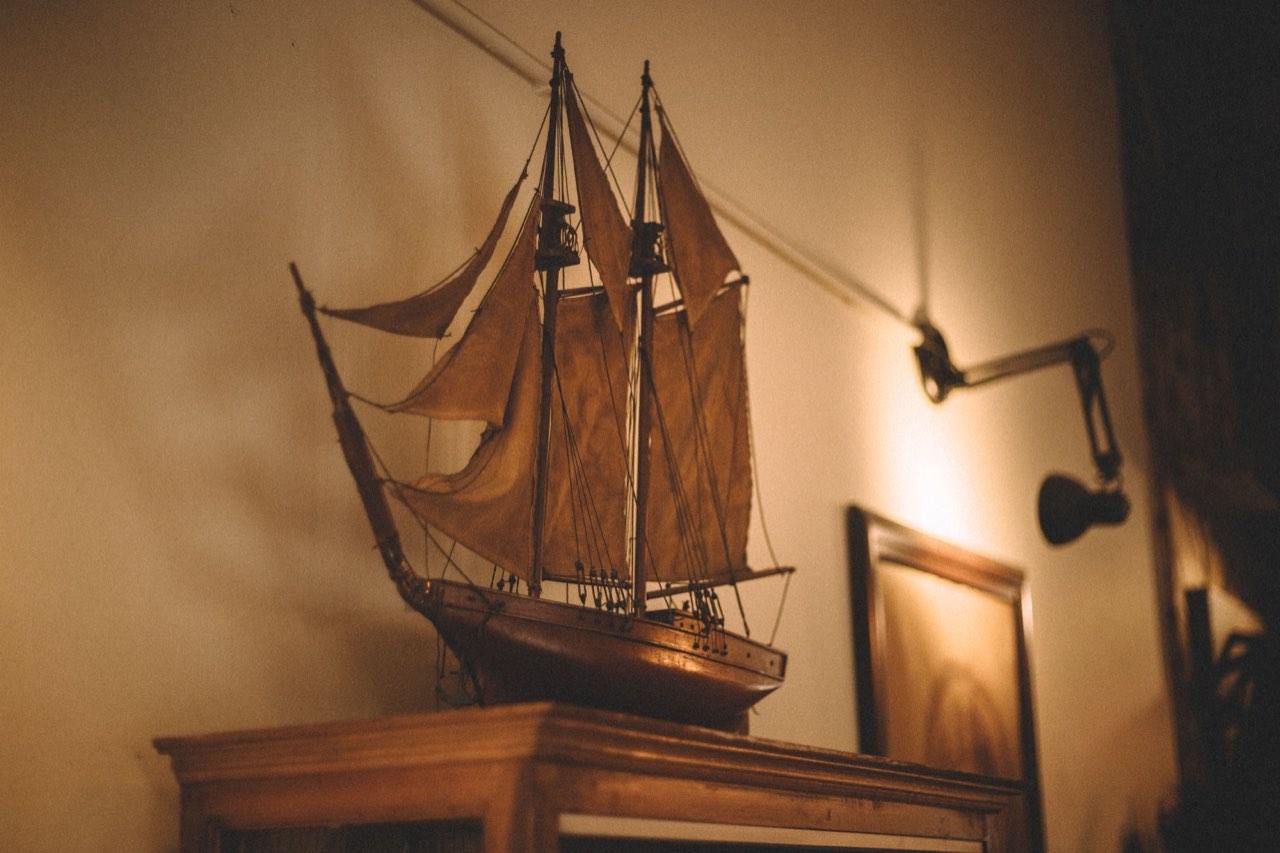 Maquette de voilier en bois à deux mâts posée sur un meuble